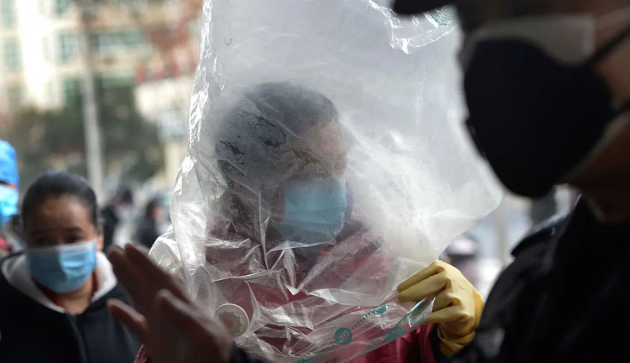 Seorang pria bermasker menutupi dirinya dengan plastik untuk melindungi diri dari wabah virus corona sebelum memasuki sebuah supermarket di Wuhan China, 10 Februari 2020. WHO mengatakan wabah virus corona COVID-19 merupakan ancaman sangat besar bagi seluruh dunia. (Chinatopix via AP)