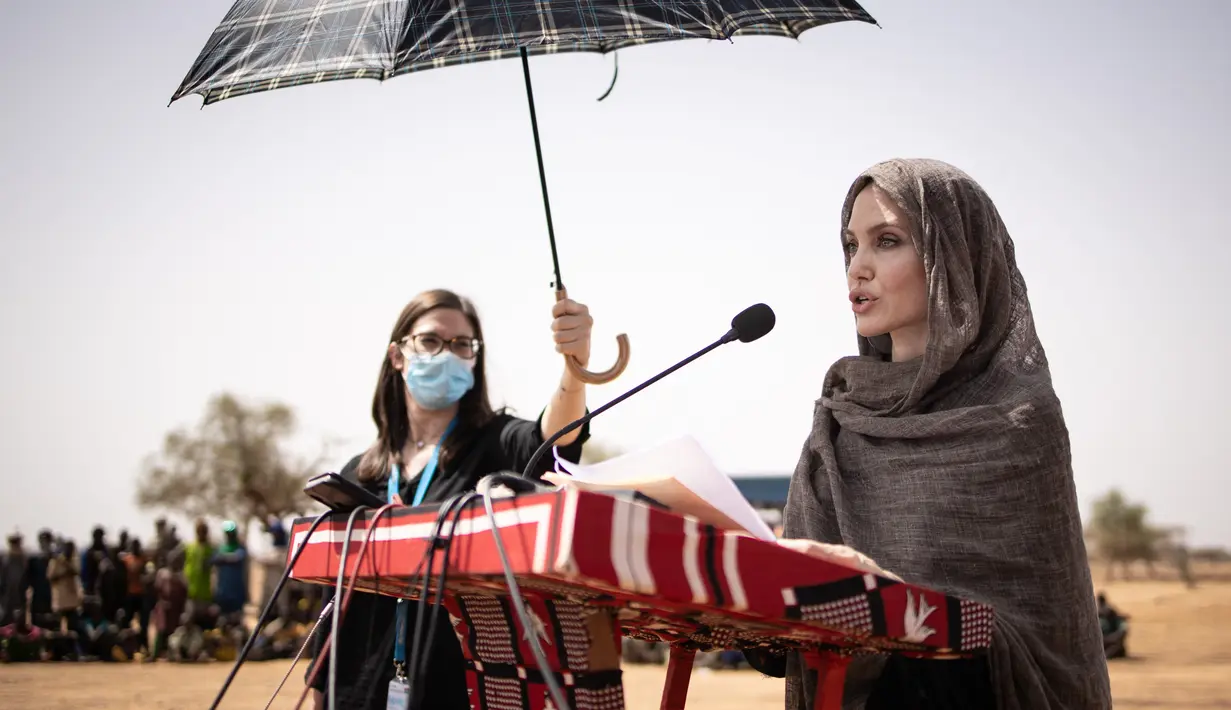 Aktris Angelina Jolie, utusan khusus PBB untuk UNHCR, memberikan pernyataan di kamp Goudebou, utara Burkina Faso, 20 Juni 2021. Angelina Jolie yang memakai kerudung dan masker juga sempat berbincang dengan para pengungsi. (OLYMPIA DE MAISMONT/AFP)