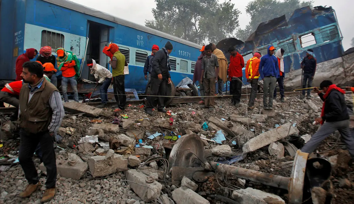 Petugas mencari korban yang masih tersisa di antara bangkai kereta api setelah terjadi kecelakaan di Pukhrayan, Kanpur, India (21/11). Menurut keterangan kepolisian setempat, korban yang meninggal tercatat lebih dari 100 orang. (Reuters/ Jitendra Prakash)