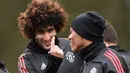 Gelandang Manchester United, Marouane Fellaini, berbincang dengan Anthony Martial saat latihan jelang laga Liga Champions di Manchester, Senin (12/3/2018). Manchester United akan berhadapan dengan Sevilla. (AFP/Oli Scarff)