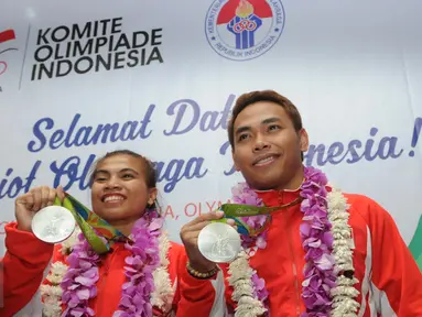 Dua atlet angkat besi Indonesia, Sri Wahyuni Agustiani dan Eko Yuli Irawan menunjukkan medali perak di Terminal 2 di Bandara Soetta, Minggu (14/08). Pemerintah menjanjikan bonus sebesar Rp 2 miliar untuk peraih medali perak. (Liputan6.com/Helmi Afandi)