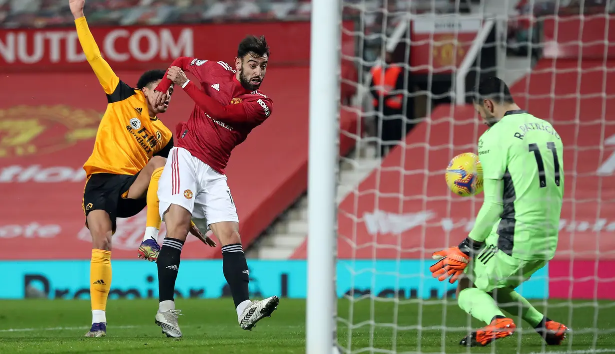 Gelandang Manchester United, Bruno Fernandes melepaskan tendangan yang mampu dihadang kiper Wolverhampton Wanderers, Rui Patricio dalam laga lanjutan Liga Inggris 2020/21 pekan ke-16 di Old Trafford, Selasa (29/12/2020). Manchester United menang 1-0 atas Wolverhampton. (AFP/Martin Rickett/Pool)