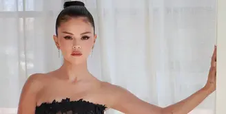 Selena Gomez memukau dengan lace hitam bernuansa couture. Meski belum terlihat di lokasi acara pada foto-foto paparazzi, Selena Gomez sempat membagikan penampilannya sebelum menghadiri pesta. Ia mengenakan gaun strapless hitam dari Oscar de la Renta Fall 2026 yang dihiasi botanical guipure lace transparan dan embroidery fringes. Siluetnya yang dramatis membuat penampilan Selena terasa seperti couture look yang pantas tampil di karpet merah.