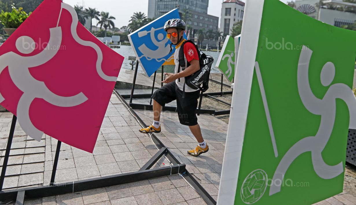 Seorang warga sedang melihat deretan logo olahraga Asian Games 2018 di Bundaran HI, Jakarta, (17/8/2017), Asian Games mengambil tema Energy Of Asia dan akan dibuka oleh Presiden Republik Indonesia Joko Widodo. (Bola.com/Nicklas Hanoatubun)