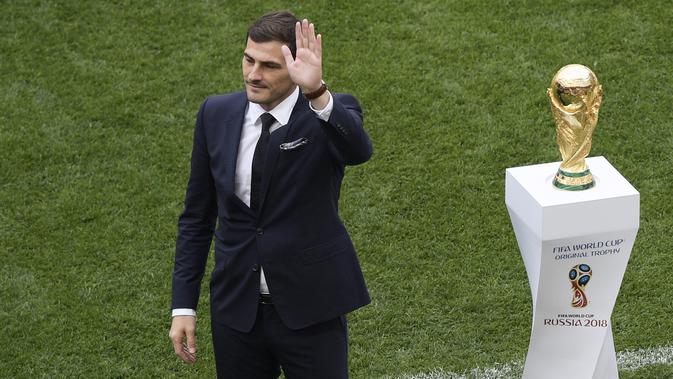 Mantan kiper timnas Spanyol, Iker Casillas melambaikan tangan di samping trofi Piala Dunia 2018 sebelum laga pembuka di stadion Luzhniki, Kamis (14/6). Trofi itu memiliki tinggi 36 centimeter dan berat 6,175 kg dengan 18 karat emas. (AFP/Mladen ANTONOV)