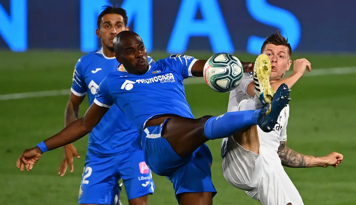 Gelandang Real Madrid, Toni Kroos, berebut bola dengan bek Getafe, Allan Nyom, pada laga lanjutan La Liga pekan ke-33 di Stadion Alfredo Di Stefano, Jumat (3/7/2020) dini hari WIB. Real Madrid menang 1-0 atas Getafe. (AFP/Gabriel Bouys)