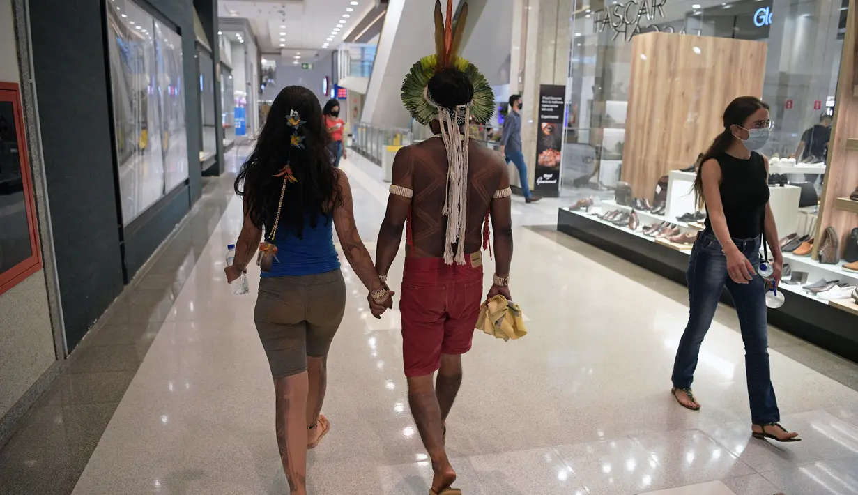 Sepasang suku Kariri berjalan di mal di Brasilia, Brasil (26/8/2021).  Ia masuk ke dalam mal saat para pengunjuk rasa suku pribumi lainnya berkumpul di ibu kota Brasil saat Mahkamah Agung bersiap untuk menangani kasus yang dapat menghilangkan keberatan di tanah leluhur mereka. (AFP/Carl De Souza)