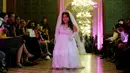 Seorang model berjalan di atas catwalk menampilkan gaun khusus perempuan bertubuh pendek dalam International Dwarf Fashion Show di Paris, Selasa (26/9). Melalui ajang, mereka ingin mendobrak standar kecantikan yang diskriminatif. (Thomas SAMSON/AFP)