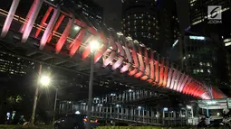 Kendaraan melintas di bawah jembatan penyeberangan orang (JPO) Gelora Bung Karno (GBK), Jakarta, Senin (25/2). JPO GBK memiliki keunikan dalam segi arsitektur dan keindahan gemerlap lampu pada malam hari. (Merdeka.com/Iqbal S Nugroho)