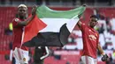 Gelandang Manchester United, Paul Pogba (kiri) dan Amad Diallo membentangkan bendera Palestina usai berakhirnya laga lanjutan Liga Inggris 2020/2021 pekan ke-37 melawan Fulham di Old Trafford Stadium, Rabu (18/5/2021). Manchester United bermain imbang 1-1 dengan Fulham. (AP/Laurence Griffiths/Pool)