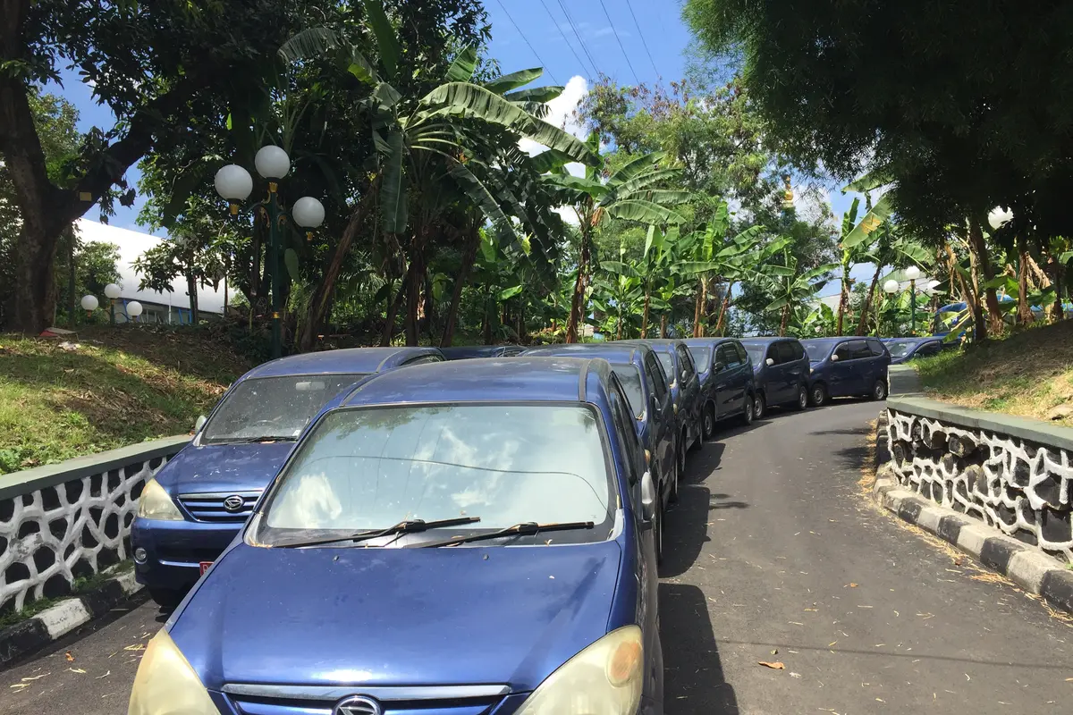 Puluhan mobil berpelat merah terparkir tanpa perawatan di halaman belakang Gedung DPR.