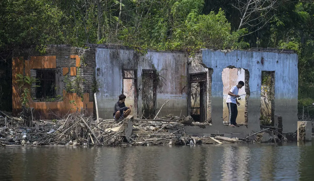 Warga memancing diantara puing bangunan rumah yang kembali muncul di kawasan Bendungan Karian yang mengering di Kampung Somang, Lebak, Banten, Kamis (30/7/2026). (AFP/ Bay Ismoyo)