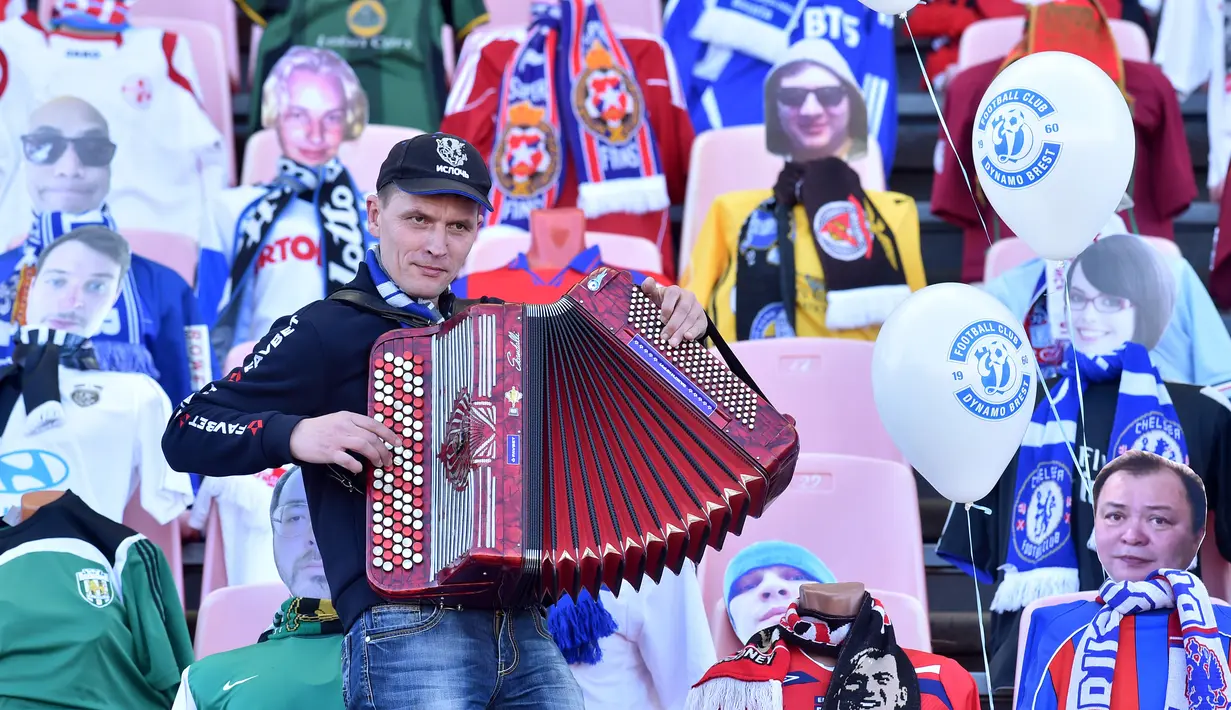 Seorang pria bermain akordion di depan maneken yang menggantikan penonton saat Liga Belarusia antara FC Dynamo-Brest dan FC Isloch di Brest, Minggu (12/4/2020). Kompetisi teratas Liga Belarusia ini menjadi satu-satunya liga di Eropa yang masih berjalan di tengah pandemi corona. (Sergei GAPON/AFP)