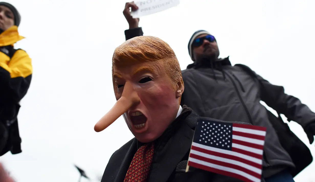 Topeng mirip Trump dengan hidung panjang mirip tokoh kartun Pinokio dikenakan demonstran saat aksi sebagai bentuk sindiran untuk Trump di Washington DC, Jumat (20/1). (AFP PHOTO / Jewel SAMAD)