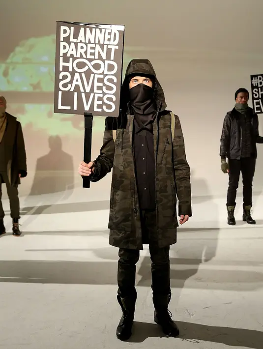 Seorang model membawa poster saat presentasi karya Robert James dalam New York Fashion Week (NYFW) di New York,AS  (30/1). Poster ini menyindir Wakil Presiden Mike Pence yang anti-aborsi. (Robin Marchant Getty Images/AFP)