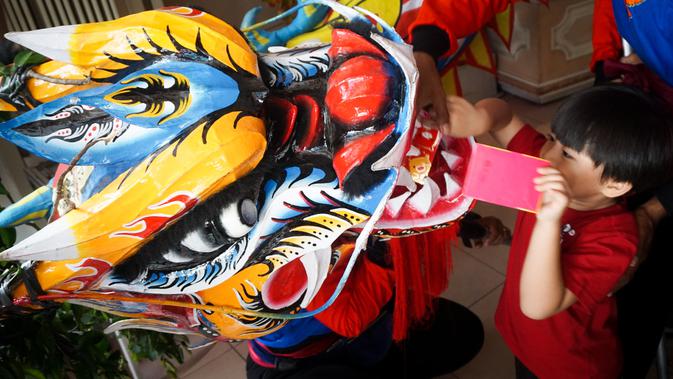 Seorang anak sedang memberikan angpau kepada liong saat kirab barongsai dan long menyambut Cap Go Meh di Solo Sabtu (8/2).(Liputan6.com/Fajar Abrori)