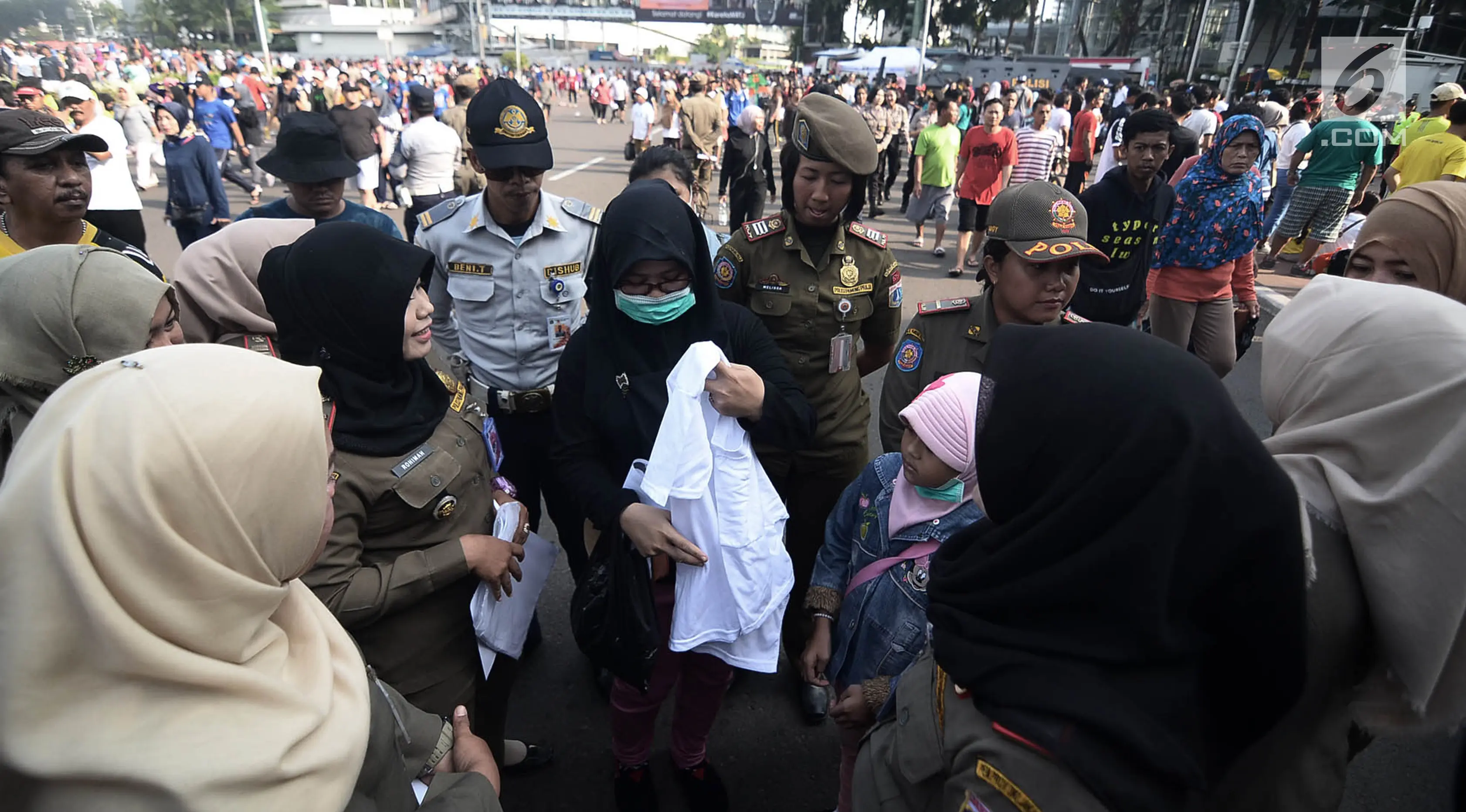 Petugas Satpol PP meminta pengunjung mengganti pakaian bertagline '#2019GantiPresiden' yang dikenakannya selama car free day (CFD), Jakarta, Minggu (6/5). Pelarangan tersebut diberlakukan sesuai Pergub No 12 Tahun 2016. (Merdeka.com/Iqbal Nugroho)