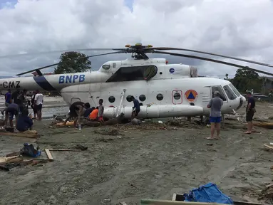Warga berusaha menggali lumpur yang menimbun helikopter Mi-17 milik BNPB pasca banjir bandang di Kabupaten Sentani, Jayapura, (17/3). Banjir bandang Sentani menewaskan 70 orang dan puluhan luka-luka. (AFP/Netty Dharma Somba)