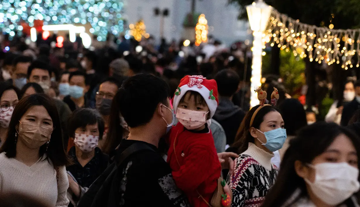 Seorang anak yang mengenakan pakaian pesta terlihat saat orang-orang berkumpul selama Natal di distrik budaya West Kowloon di Hong Kong (25/12/2021). Pohon Natal raksasa didekorasi secara glamor dengan karangan bunga dan ornamen, berkilauan dengan lampu meriah yang cerah. (AFP/Bertha Wang)