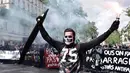 Seorang pria memegang bendera sambil manyalakan suar asap saat demonstrasi perayaan May Day di Paris, Prancis,Senin (1/5). Hari Buruh Internasional atau May Day di Paris, diwarnai bentrokan antara pengunjuk rasa dengan polisi.  (PHILIPPE LOPEZ/AFP)