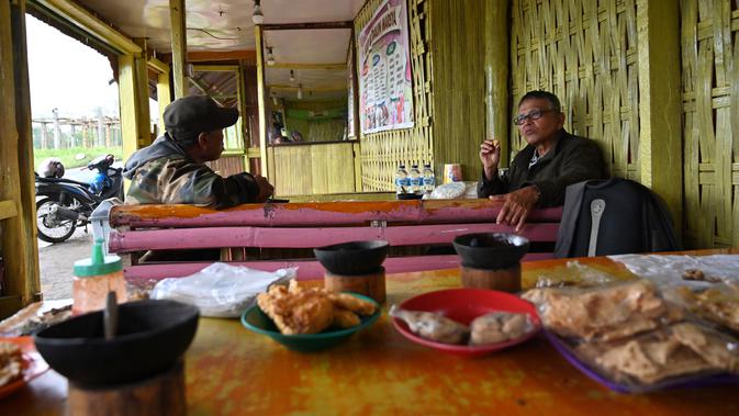 Dua pria menikmati kopi Kawa Daun di sebuah kafe tradisional, Tabek, Sumatera Barat (29/11). Kopi Kawa Daun adalah minuman kuno yang berasal dari masa kolonial ketika sedikit penduduk setempat yang mampu membeli kopi yang diekstrak. (AFP Photo/Adek Berry)