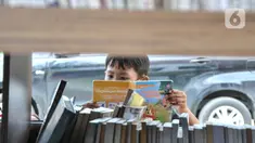 Seorang anak membaca buku di Perpustakaan Keliling kawasan Jatinegara, Jakarta, Rabu (29/9/2021). Mobil Perpustakaan Keliling yang difasilitasi Dinas Perpustakaan dan Kearsipan DKI itu merupakan sarana dan upaya pemerintah dalam meningkatkan minat baca anak sejak dini. (merdeka.com/Iqbal S Nugroho)