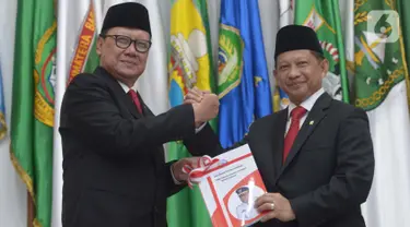 Menteri Dalam Negeri Tito Karnavian (kanan) menerima buku dari pejabat lama Tjahjo Kumolo saat  acara serah terima jabatan di Kantor Kemendagri, Jakarta, Rabu (23/10/2019). Presiden Jokowi resmi melantik Tito Karnavian menjadi mendagri dalam jajaran Kabinet Indonesia Maju. (merdeka.com/Imam Buhori)