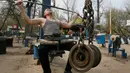 Seorang pria berlatih mengangkat beban di outdoor gym atau pusat kebugaran terbuka di tepi Sungai Dnipro, Kiev, Ukraina, Kamis (18/4). Pusat kebugaran terbuka ini terbilang unik karena memanfaatkan besi tua sebagai alat fitness. (AP Photo/Efrem Lukatsky)