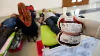 Petugas Palang Merah Indonesia (PMI) menunjukan darah yang sudah dimasukan ke Jakarta, Minggu (3/12). Kegiatan donor darah tersebut diadakan dalam rangkaian acara Natal. (Liputan6.com/JohanTallo)
