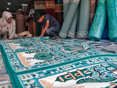Pekerja mengecek karpet masjid pesanan pembeli di sebuah toko di kawasan Tanah Abang, Jakarta, Kamis (16/3/2023). (Liputan6.com/Angga Yuniar)