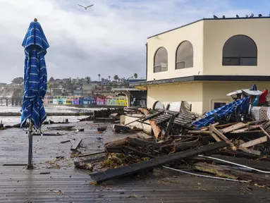 Puing-puing badai didorong ke atas Tacos Morenos di Capitola, California, Kamis (5/1/2023). Angin topan yang merusak, ombak bergelombang dan hujan lebat dari "sungai atmosfer" yang kuat menghantam California pada hari Kamis, melumpuhkan listrik hingga puluhan ribu, menyebabkan banjir, dan mengakibatkan kematian setidaknya dua orang, termasuk seorang anak yang rumahnya dihantam pohon tumbang. (AP Photo/Nic Coury)