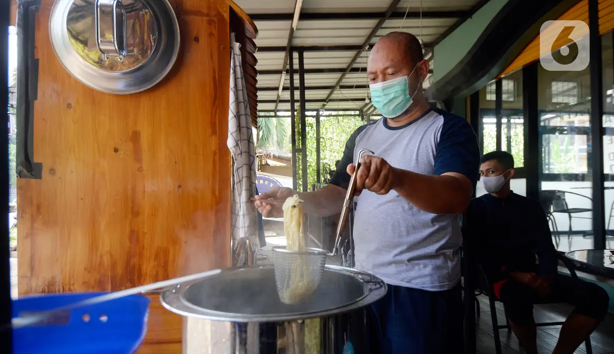 Megah Putra Perkasa, pilot komersial maskapai nasional di Tanah Air, meracik mie ayam di kiosnya Kawasan BSD City, Tangerang Selatan, Rabu (12/8/2020). Masa pandemi yang membuat jasa penerbangan harus terhenti ini membuat Megah Putra banting setir menjadi penjual mie ayam. (merdeka.com/Dwi Narwoko)
