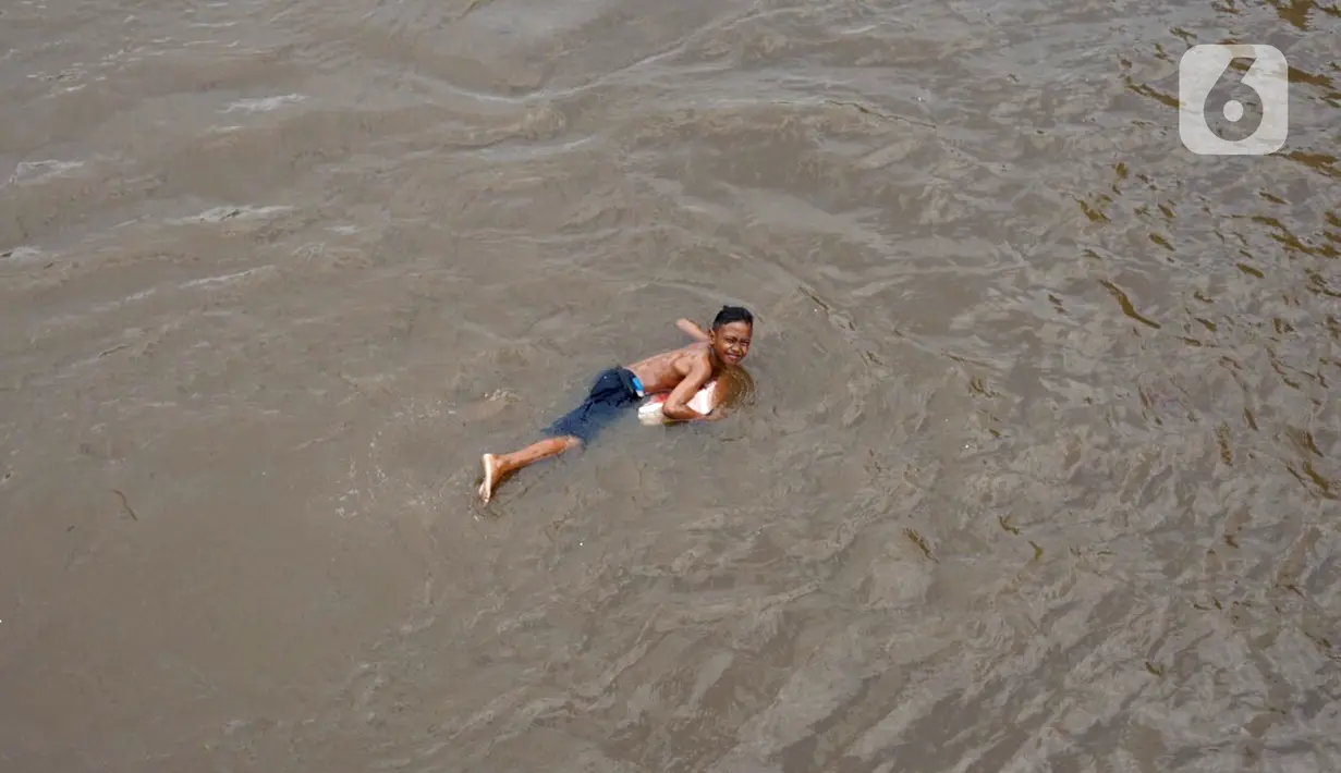 Anak-anak berenang di aliran Sungai Ciliwung, Jatinegara, Jakarta Timur, Sabtu (4/7/2020). Minimnya lahan bermain menyebabkan anak-anak tersebut bermain tidak pada tempatnya, meski dapat membahayakan keselamatan. (Liputan6.com/Immanuel Antonius)
