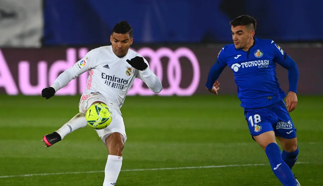 Gelandang Real Madrid, Casemiro (kiri) menembak bola dari kawalan gelandang Getafe, Mauro Arambarri pada pertandingan lanjutan La Liga Spanyol di stadion Alfredo di Stefano di Madrid, Spanyol, Rabu (10/2/2021). Kemenangan ini membuat Madrid naik ke peringkat kedua klasemen. (AFP/Gabriel Bouys)