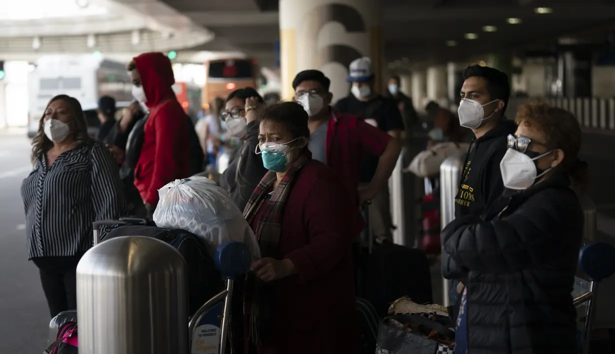 Pelancong menunggu bus antar-jemput tiba di Bandara Internasional Los Angeles di Los Angeles, Senin (20/12/2021). Departemen Kesehatan Masyarakat Los Angeles County melaporkan lebih dari 3.500 kasus baru COVID-19 pada hari Minggu. (AP Photo/Jae C.Hong)