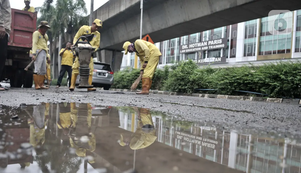 Petugas Dinas Bina Marga menambal jalan berlubang di kawasan Kelapa Gading, Jakarta, Minggu (1/3/2020). Kepala Dinas Bina Marga DKI Jakarta Hari Nugroho menyebut banjir pada Februari 2020 merusak 495 jalan Ibu Kota dengan 3.290 titik lubang yang tersebar di lima wilayah. (merdeka.com/Iqbal Nugroho)