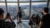 Pengunjung berpose untuk foto di bagian lantai kaca gedung pencakar langit Lotte World Tower 123 lantai di Seoul pada 22 September 2021. Bangunan tertinggi di Korea Selatan tersebut berlokasi di pinggiran Sungai Han, ibu kota Seoul. (Anthony WALLACE / AFP)