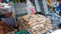 Seorang pedagang tusuk sate dan arang sedang menunggu pembeli di Pasar Kebayoran Lama, Jakarta, Rabu (28/6/2023). (Liputan6.com/Angga Yuniar)