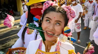 Seorang wanita menusuk pipinya dengan besi  saat mengikuti prosesi perayaan Festival Vegetarian tahunan di Phuket, Thailand, Kamis (3/10/2019). Festival ini biasanya berlangsung selama 9 hari di akhir September sampai Oktober. (AFP Photo/Mladen Antonov)