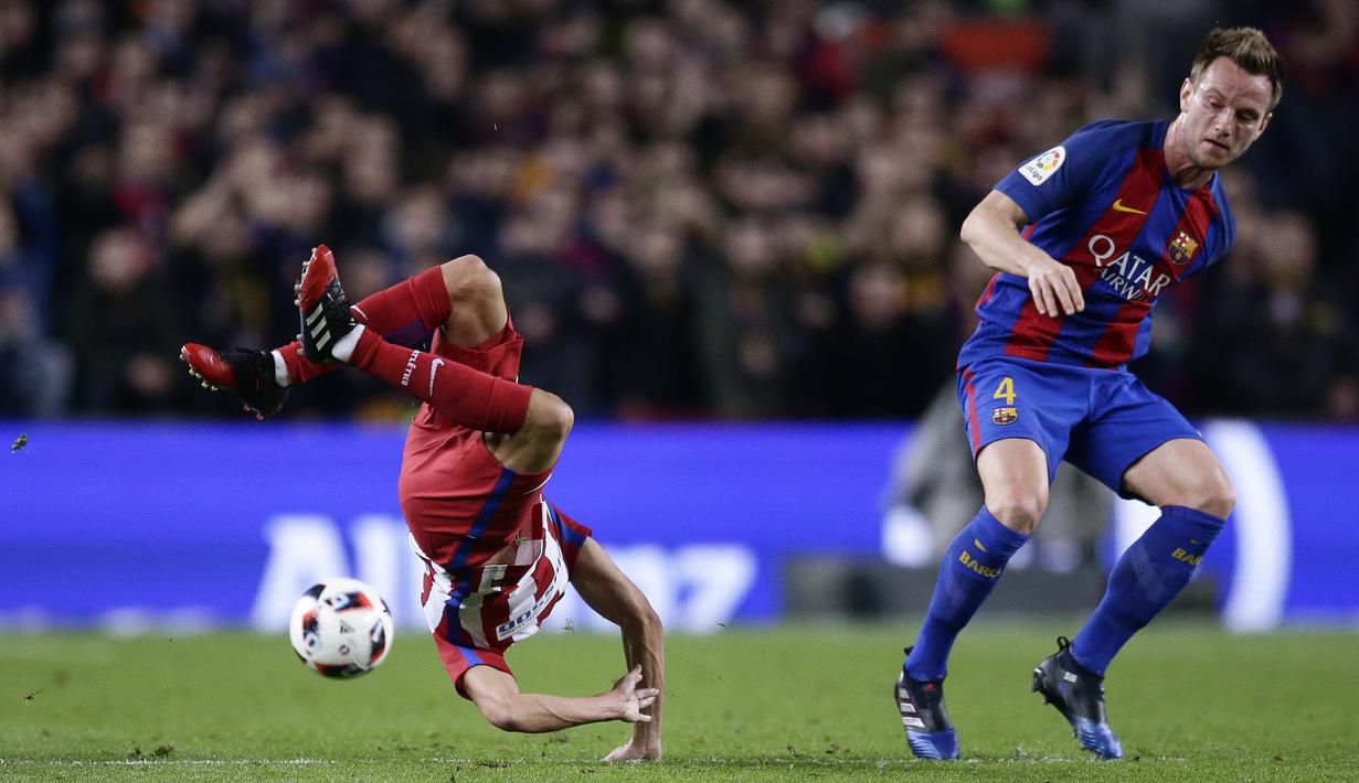 Pemain Atletico, Nico Gaitan terjatuh saat mencoba menghadang pemain Barcelona, Ivan Rakitic pada leg kedua semifinal Copa del Rey semifinal di Camp Nou stadium, Barcelona (7/2/2017). Barcelona bermain imbang 1-1. (AP/Manu Fernandez)