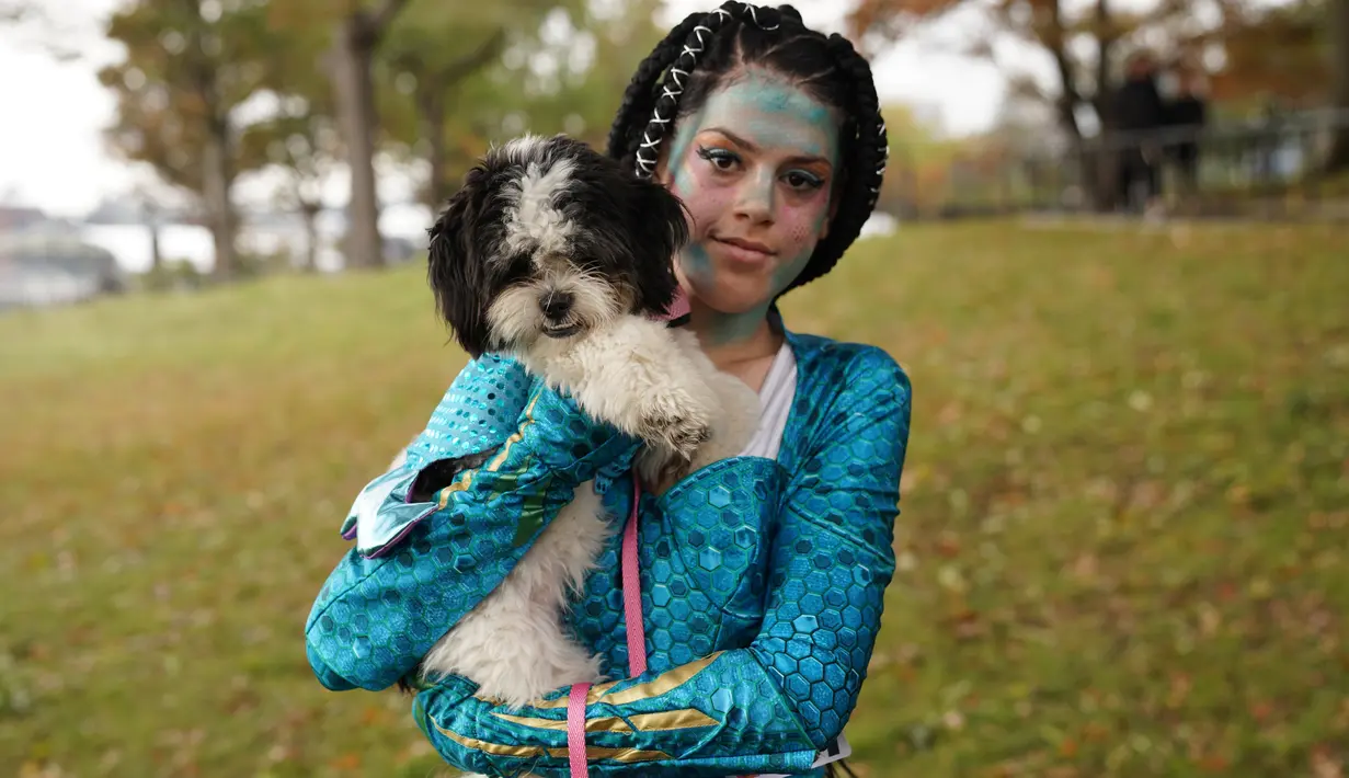 Seekor anjing dan pemiliknya dalam kostum terlihat selama Parade Tompkins Square Halloween Dog di New York, 27 Oktober 2018. Anjing dengan kostum yang paling unik akan dinobatkan sebagai pemenang dan mendapat hadiah dari panitia. (TIMOTHY A. CLARY / AFP)