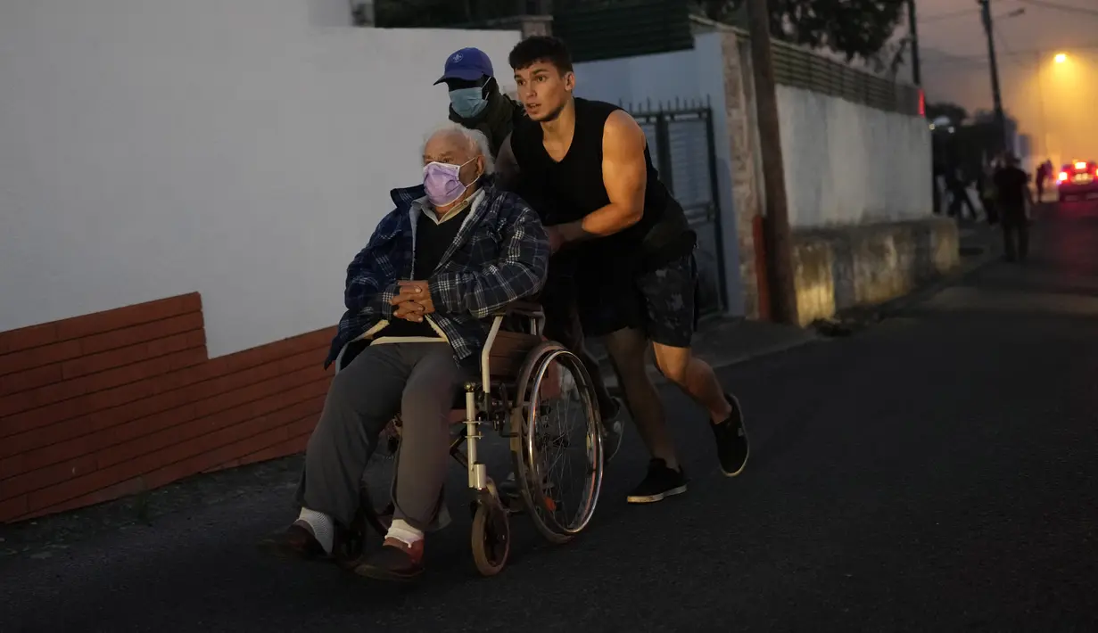 Penduduk setempat dievakuasi saat api mendekati rumah mereka di Alcabideche, di luar Lisbon, Portugal, Selasa (25/7/2023). (AP Photo/Armando Franca)
