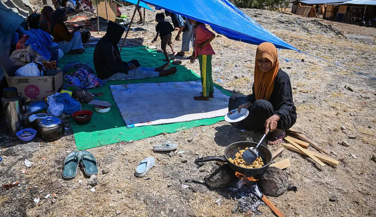 Seorang warga memasak di dekat tenda di sebuah lapangan terbuka di Marapokot, Nagekeo, Nusa Tenggara Timur, Senin, 17 Agustus 2026, (AFP/ Juni Kriswanto)