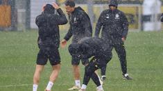Para pemain Dortmund di sekitar Felix Nmecha (tengah) dikejutkan dengan hujan deras saat sesi latihan di Dortmund, Jerman, Senin (15/4/2024). (Bernd Thissen/dpa via AP)