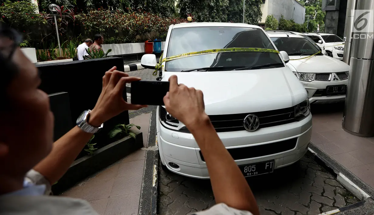 Seorang pria mengambil gambar salah satu mobil milik bos PT First Travel Andika Surachman dan Anniesa Desvitasari Hasibuan yang terparkir di Bareskrim Polri, Gedung Kementerian Kelautan dan Perikanan, Jakarta, Jumat (25/8). (Liputan6.com/Johan Tallo)