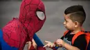 Jahn Fredy Duque berbincang dengan seorang bocah di jalanan Bogota, Kolombia, Senin (24/4). Duque mencari nafkah dengan melakukan atraksi layaknya Spiderman. (AFP Photo/RAUL ARBOLEDA)