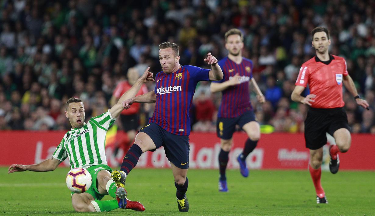Gelandang Barcelona, Arthur Melo, berusaha melewati pemain Real Betis, Tello, pada laga La Liga 2019 di Stadion Benito Villamarin, Minggu (17/3). Barcelona menang 4-1 atas Real Betis. (AP/Miguel Morenatti)