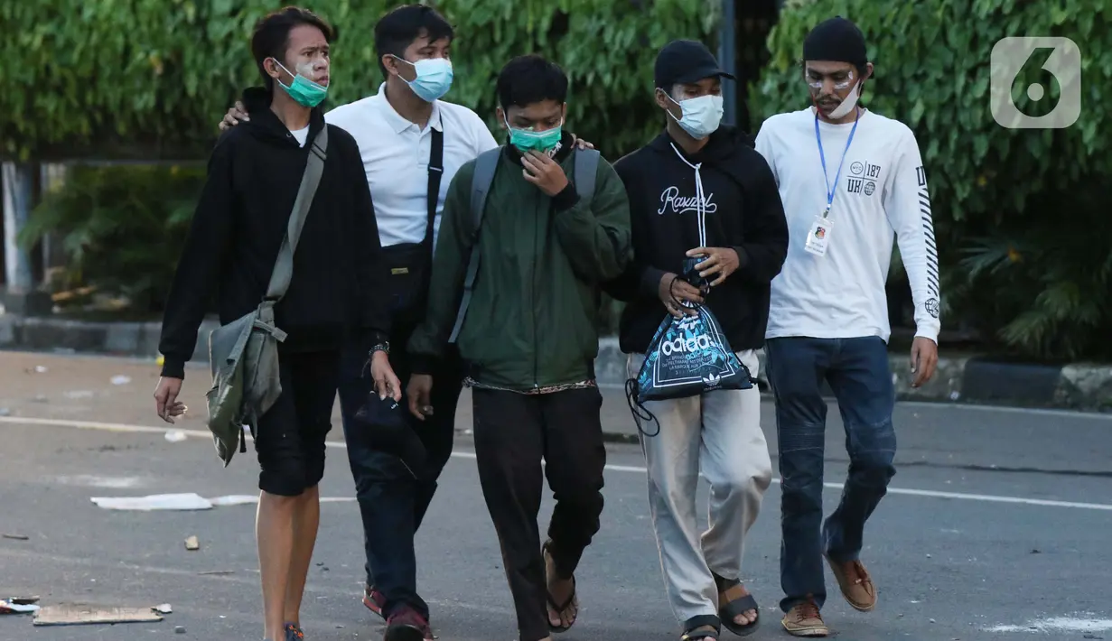 Polisi berpakaian kaus putih mengamankan tiga orang pemuda yang dicurigai terlibat kericuhan di kawasan Tugu Tani, Jakarta, Selasa (13/10/2020). Sejumlah pemuda diamankan polisi karena dicurigai terlibat kericuhan di kawasan Tugu Tani. (Liputan6.com/Helmi Fithriansyah)