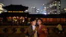 Gambar pada 4 Oktober 2019, wisatawan memainkan ponsel mereka saat kunjungan malam ke Istana Gyeongbokgung di pusat Seoul, Korea Selatan. Kunjungan malam tersedia pada minggu ketiga dan keempat setiap bulan mulai dari 26 April sampai 31 Oktober, kecuali pada bulan Agustus. (Photo by Ed JONES / AFP)