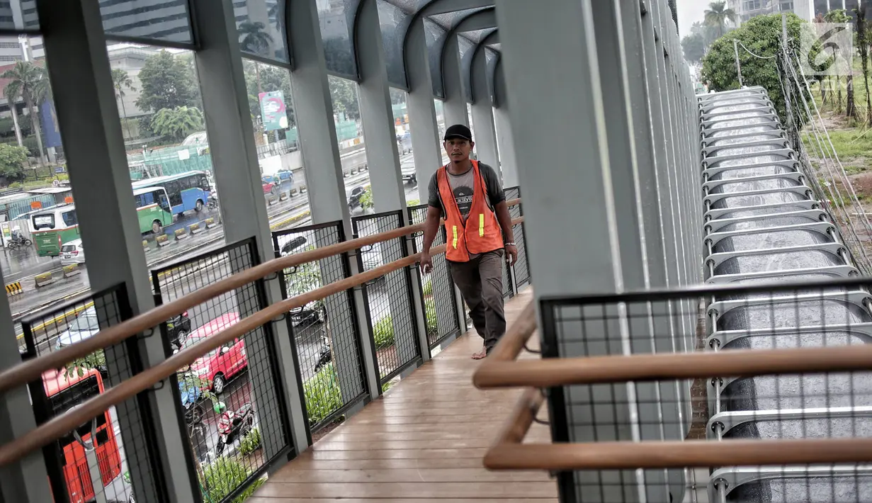 Pekerja melintas di jembatan penyeberangan orang (JPO) Bundaran Senayan, Jakarta, Senin (21/1). (Liputan6.com/Faizal Fanani)